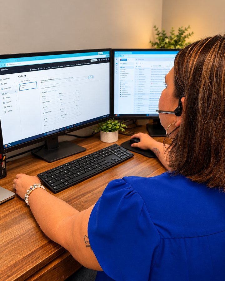 Mark Johnson & Sons Plumbing team member wearing a headset at a dual-monitor office desk