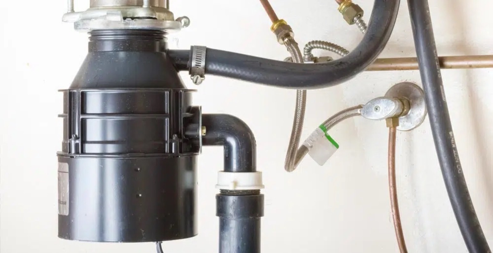 Mark Johnson & Sons Plumbing technician installing a new garbage disposal under a North Louisiana kitchen sink